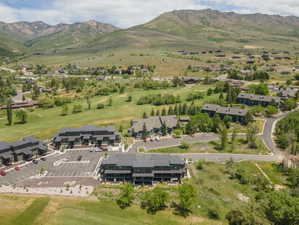 Community of townhomes and apartment-style buildings surrounded by expansive green spaces and mountainous terrain