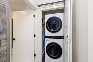 Compact laundry area featuring a stacked washer and dryer unit, a space-saving barn door, and a built-in shelf