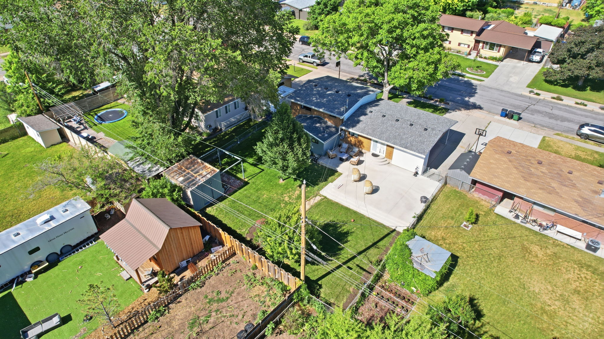 Expansive property featuring a large concrete patio, mature trees, a detached storage shed, and a fenced perimeter