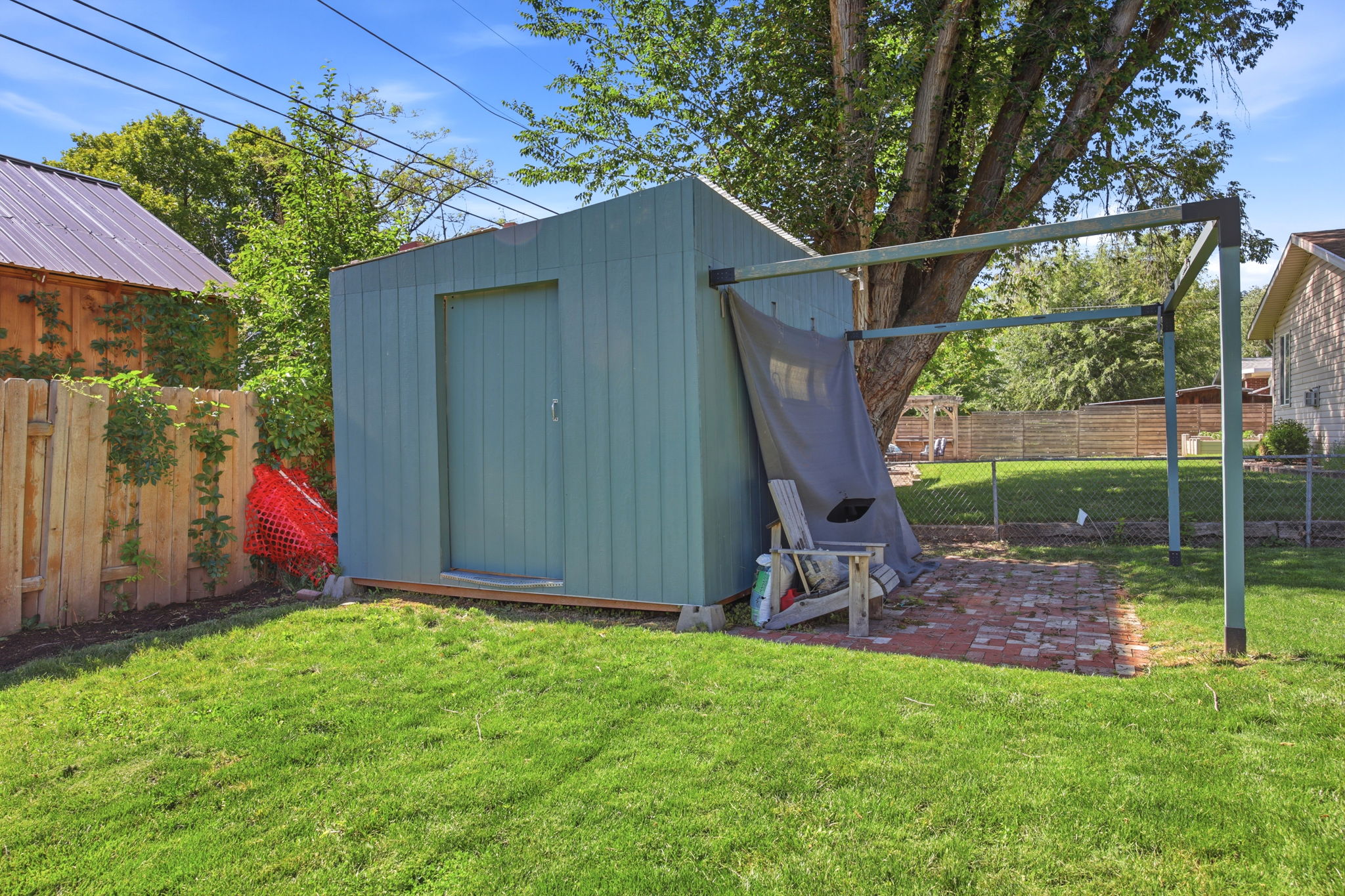 Storage shed with vertical siding, accompanied by a brick patio