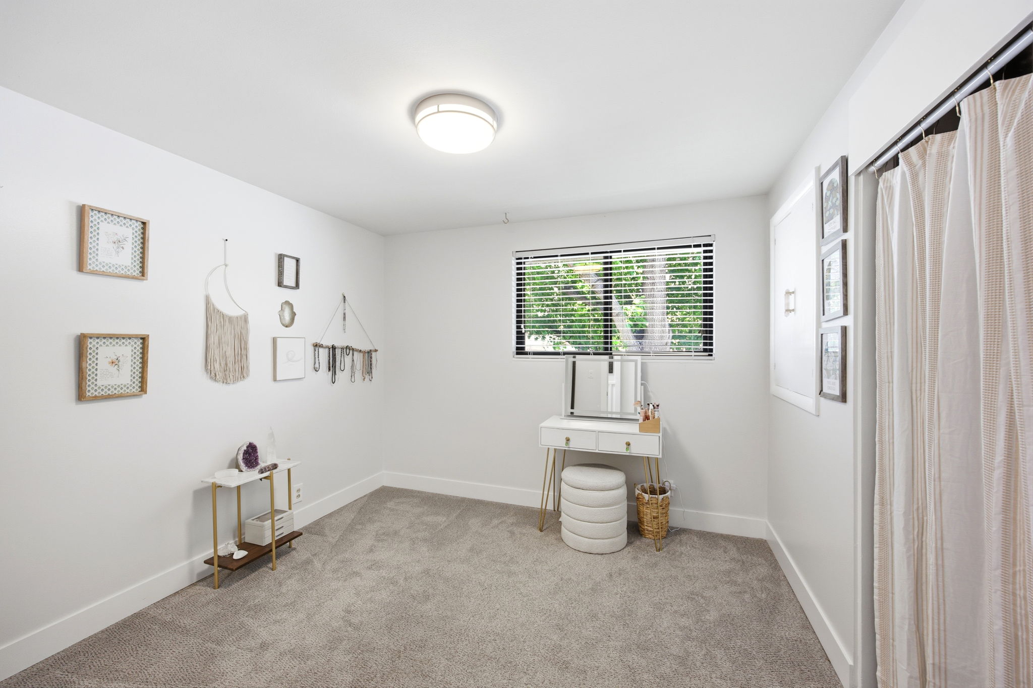 Bright interior space featuring light gray carpeting, crisp white walls, and a window with horizontal blinds