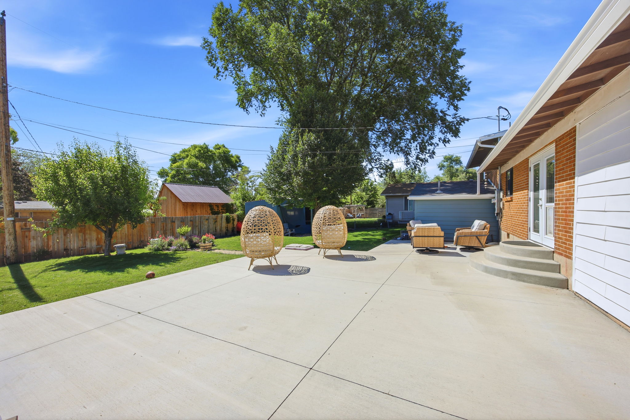 Spacious concrete patio featuring a tiered entry, a brick exterior, and white siding