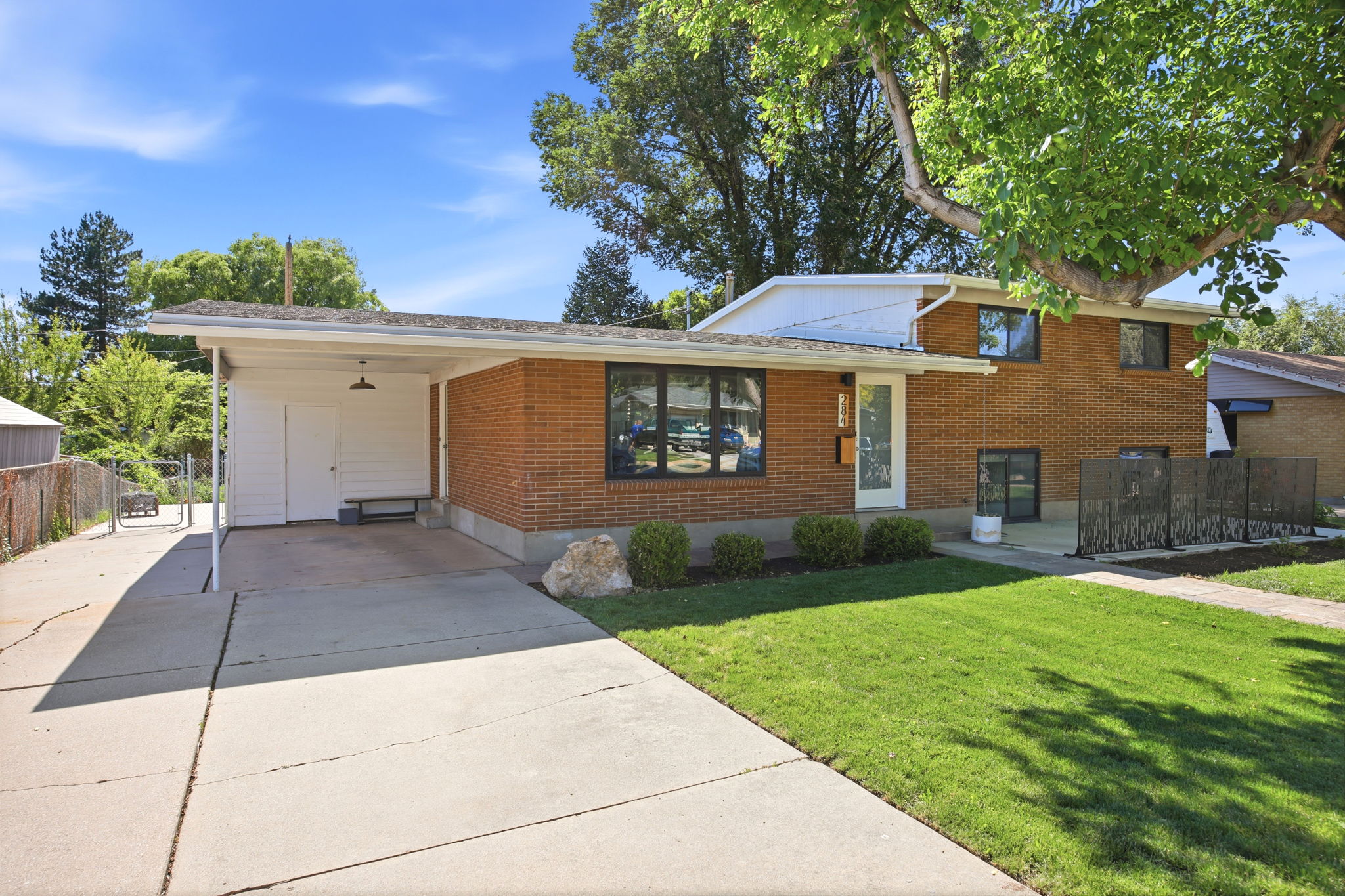 Brick exterior with a covered carport featuring a storage shed and concrete driveway