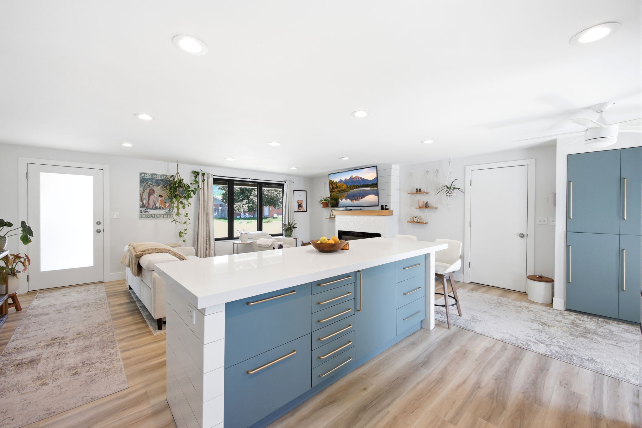 Open-concept living space featuring a central kitchen island with blue cabinetry and a white countertop
