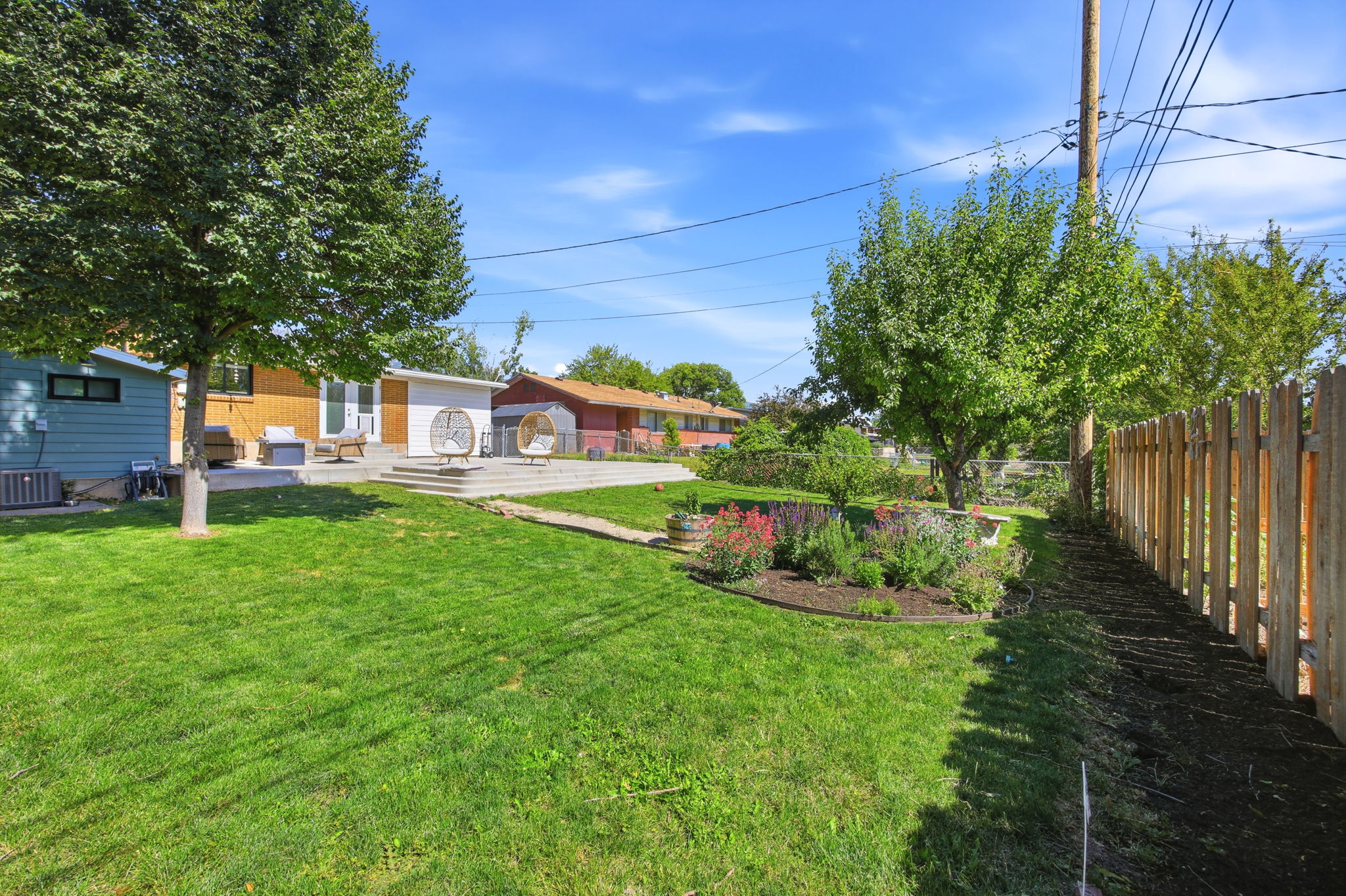 Expansive green lawn with mature trees and a wood picket fence