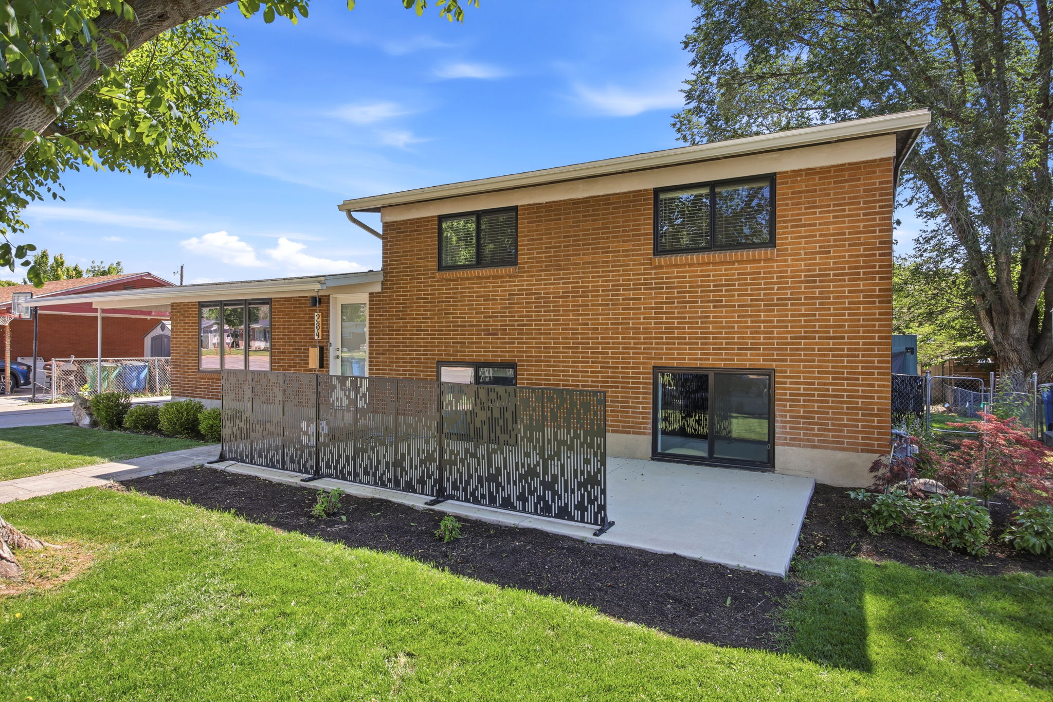 Brick exterior with a contemporary privacy screen and an expansive green lawn