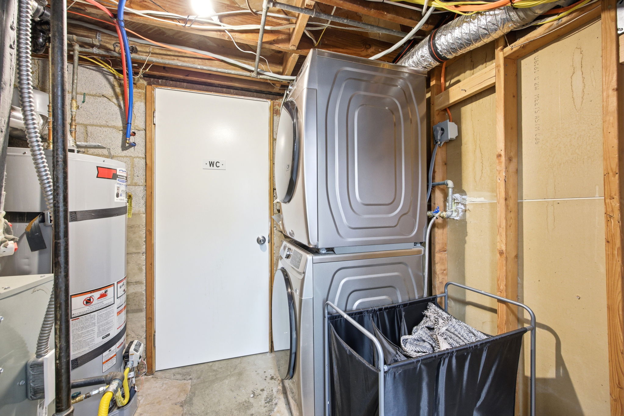 Utility area featuring a water heater, visible plumbing, and exposed ceiling joists