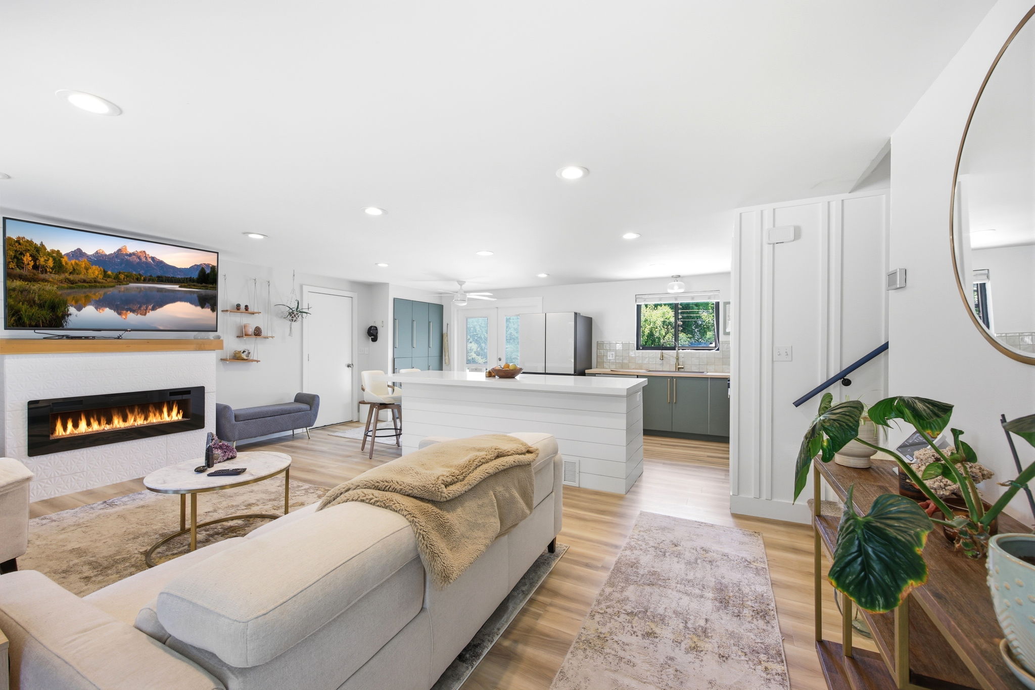 Open-concept living space featuring wood-finish flooring, a contemporary linear fireplace with a white tile surround, and recessed lighting