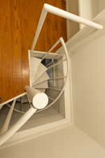 White spiral staircase with an overhead railing, complementing the warm wood-finish flooring