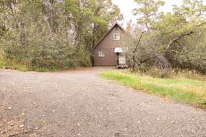A-frame style residence with a brown exterior and white trim, surrounded by mature trees