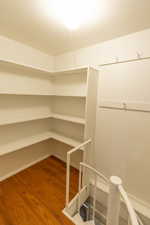 Corner shelving with white finishes, wood-finish flooring, recessed lighting, and a white spiral staircase