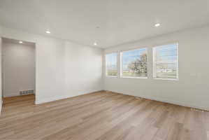 **DISCLAIMER** Interior package may vary. Open-concept living area featuring light wood-finish flooring, recessed lighting, and three large windows with white blinds
