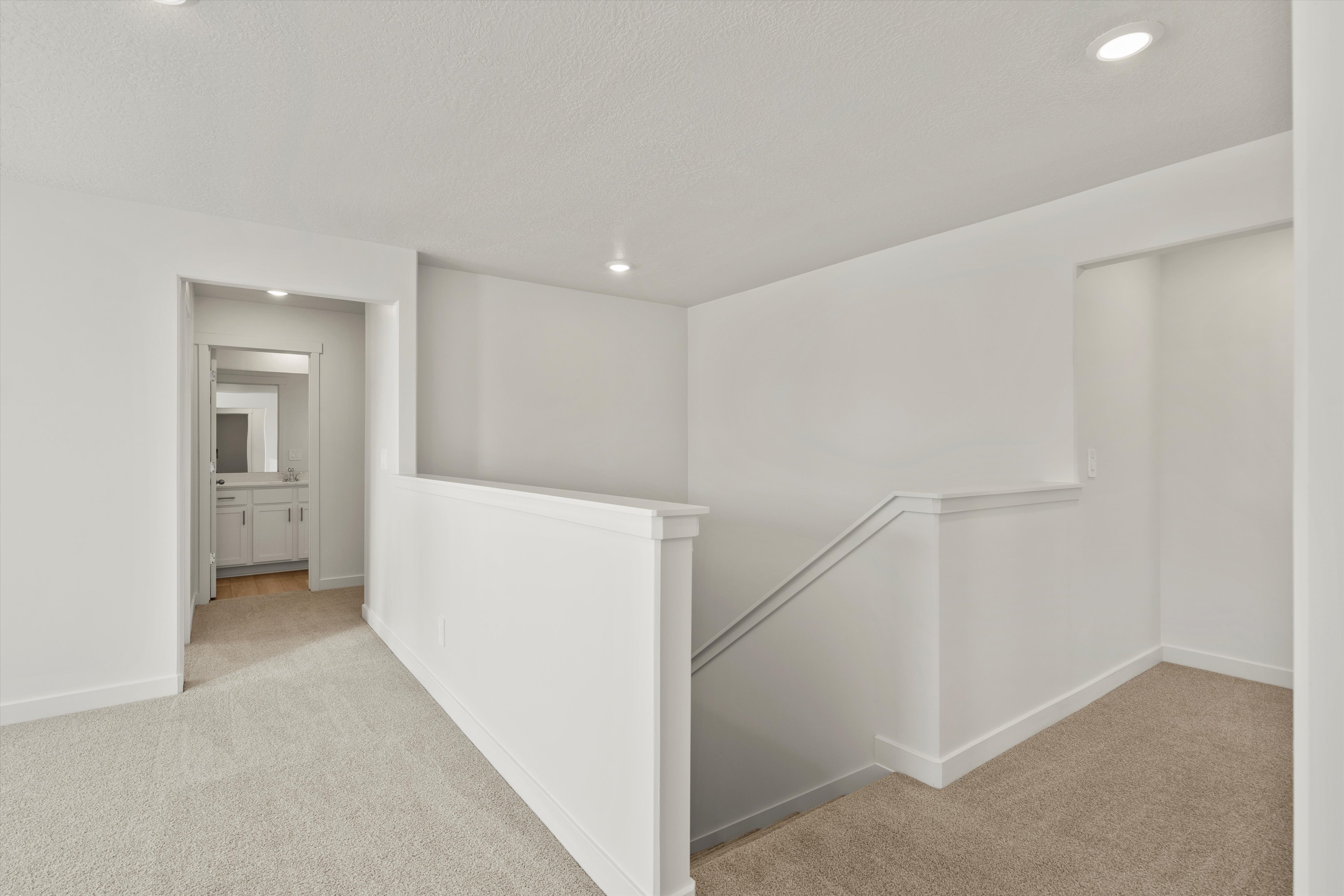 **DISCLAIMER** Interior package may vary. Upper-level landing featuring neutral carpeting, recessed lighting, and a white stair railing