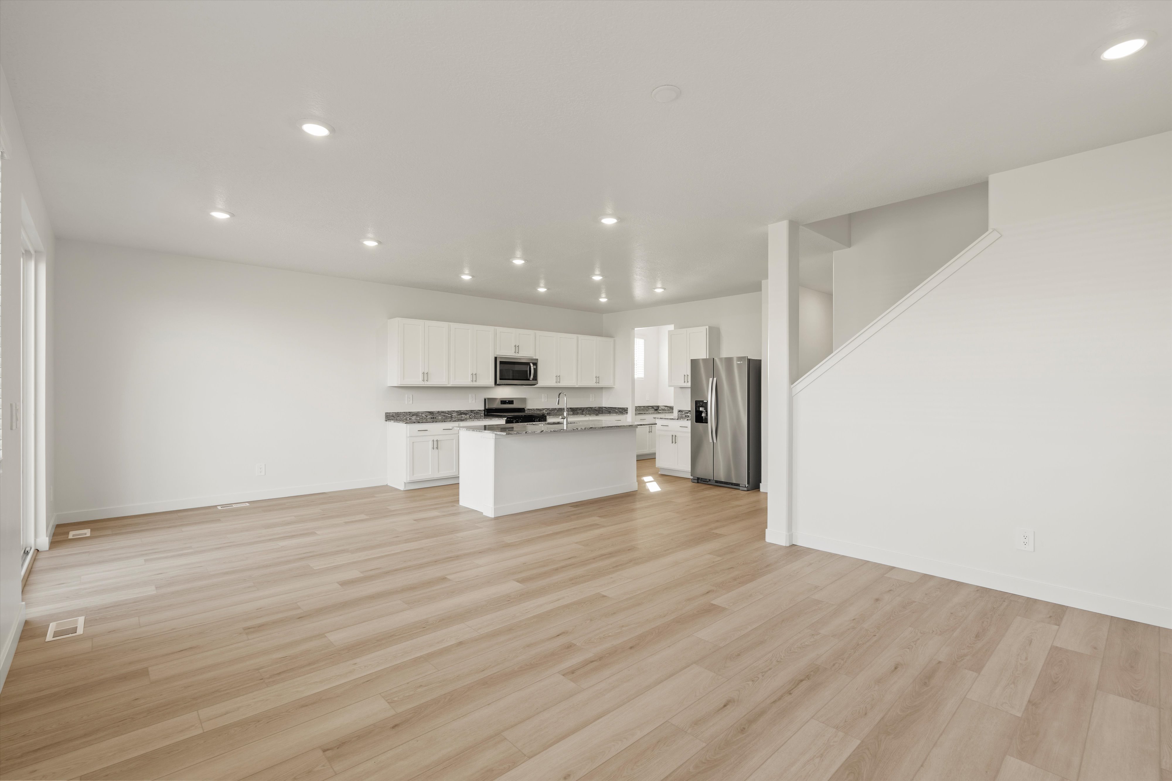**DISCLAIMER** Interior package may vary. Open-concept living area featuring light wood-finish flooring, recessed lighting, and a modern kitchen