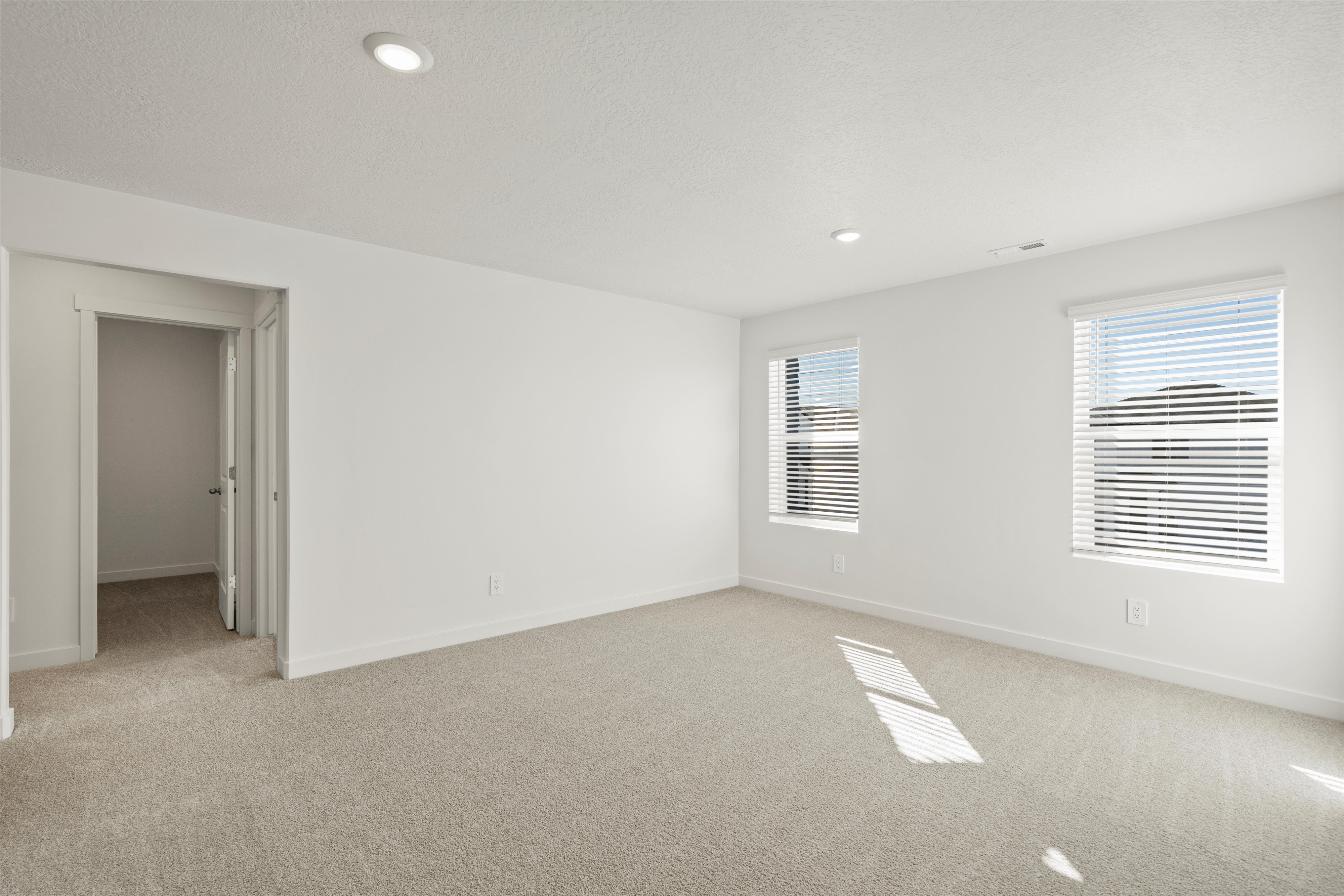 **DISCLAIMER** Interior package may vary. Spacious room featuring neutral carpeting, recessed ceiling lighting, two windows with blinds, and white walls