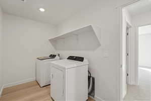 Dedicated laundry area featuring wood-finish flooring, white walls, recessed ceiling lighting, and a wall-mounted storage shelf
