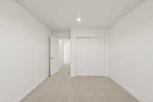 **DISCLAIMER** Interior package may vary. Carpeted room featuring a white interior door, white bi-fold closet doors, white baseboards, and a recessed ceiling light