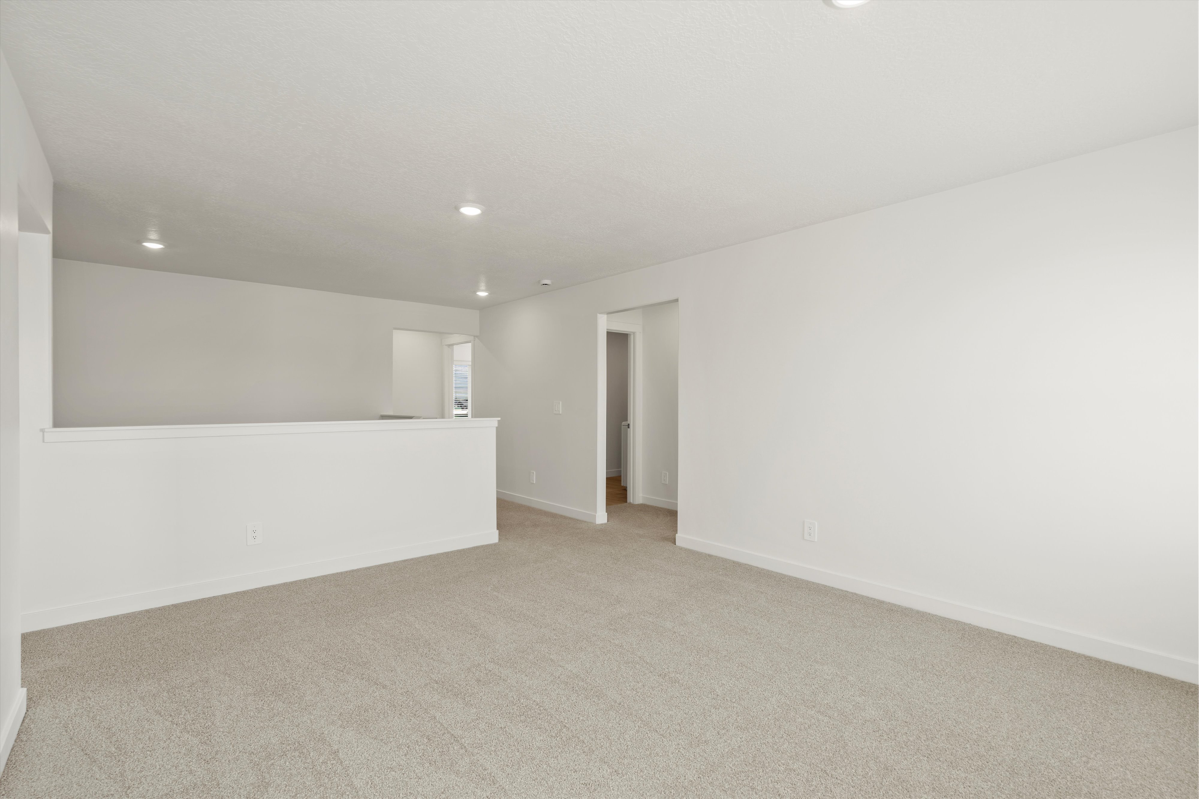**DISCLAIMER** Interior package may vary. Spacious carpeted room featuring recessed lighting, light neutral wall paint, white trim, and a partial wall separation