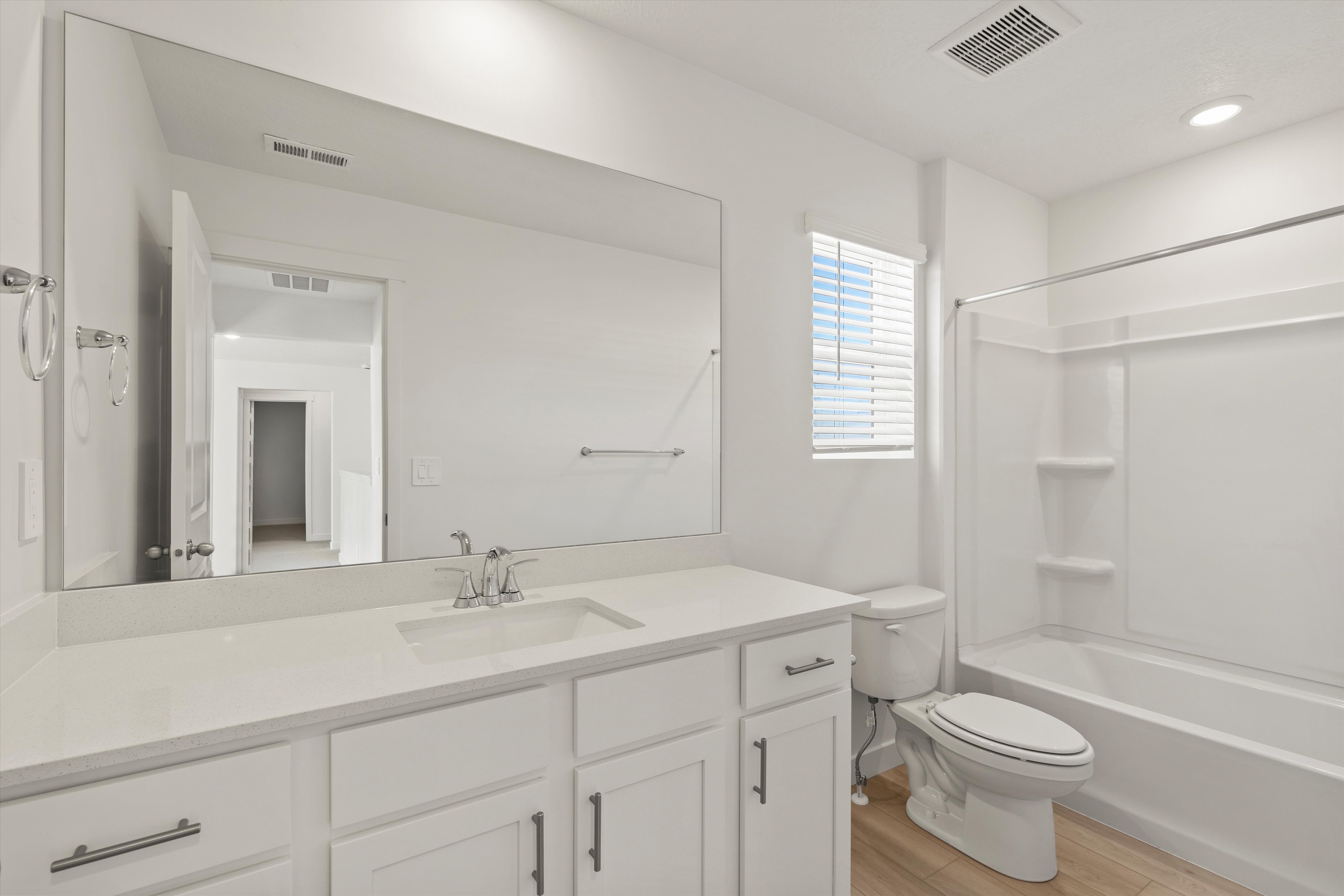 **DISCLAIMER** Interior package may vary. Bathroom featuring a spacious vanity with an integrated sink, polished chrome faucet, white cabinetry, and a large frameless mirror