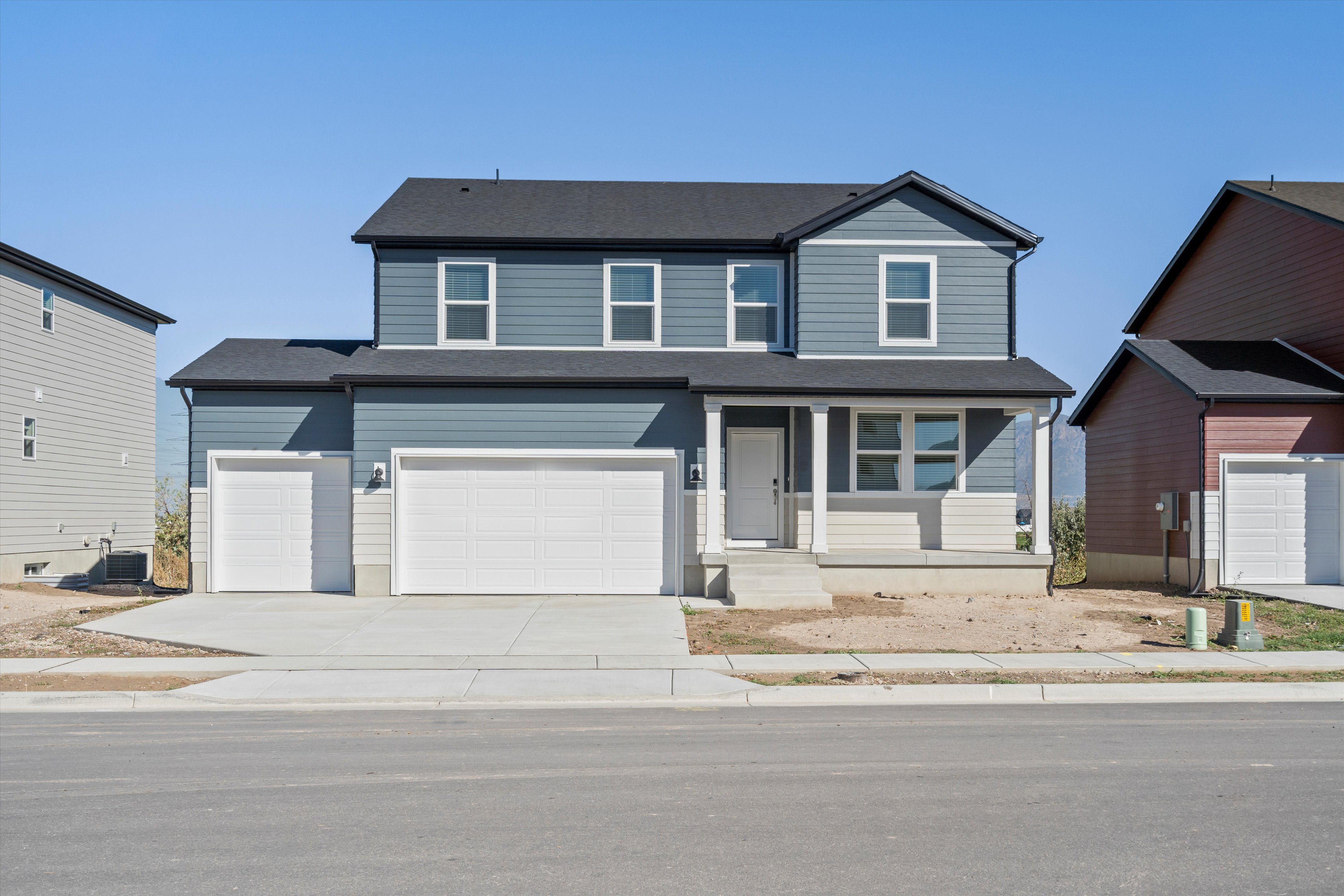 Two-story residence featuring a covered front porch, two-tone siding, a two-car garage, and a single-car garage