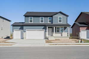 Two-story residence featuring a covered front porch, two-tone siding, a two-car garage, and a single-car garage