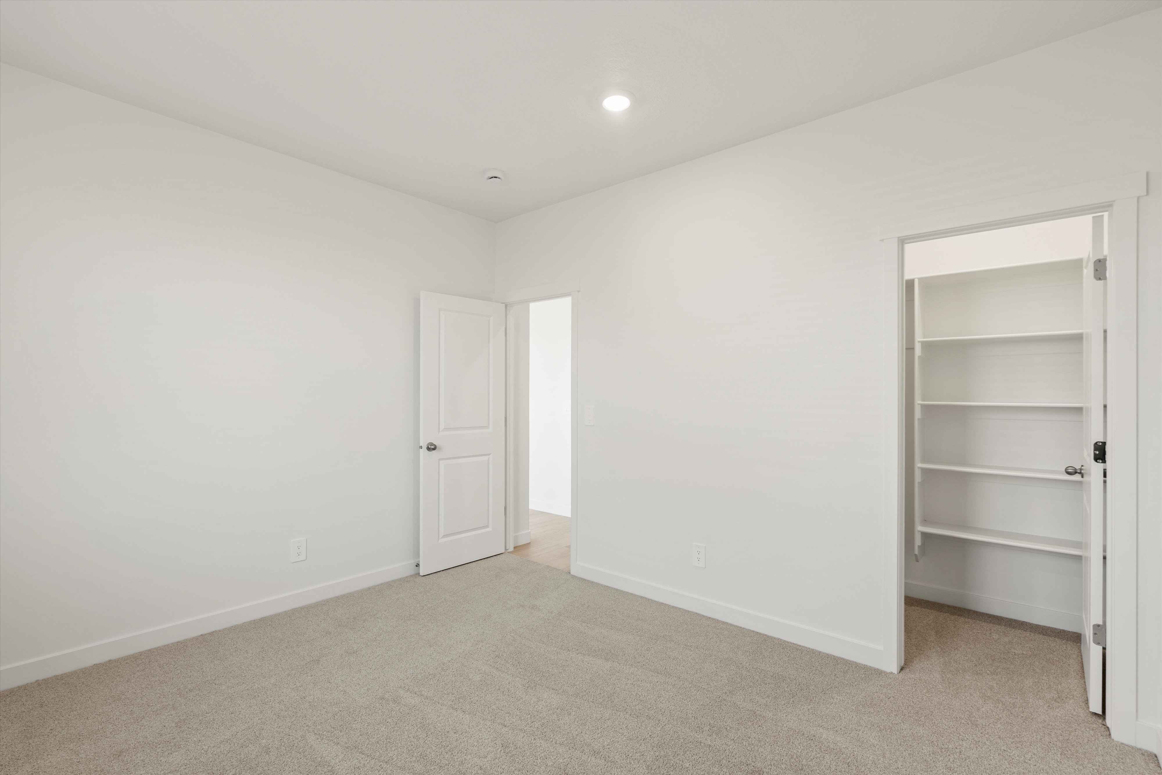 **DISCLAIMER** Interior package may vary. Neutral toned room featuring plush carpeting, a built-in closet with shelving, and a recessed ceiling light