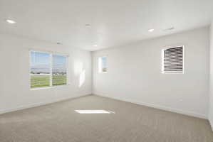 **DISCLAIMER** Interior package may vary. Bright room featuring a large window with horizontal blinds, neutral wall paint, recessed lighting, and soft carpet flooring