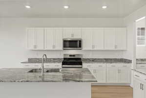 **DISCLAIMER** Interior package may vary. Kitchen featuring an island with an undermount double basin sink and a high-arc faucet, granite countertops, white shaker cabinetry with brushed nickel hardware, stainless steel appliances, and recessed lighting