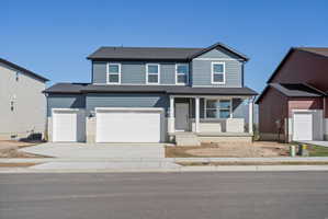 Contemporary two-story residence featuring a covered front porch, dark gray siding, light beige stone veneer accents, and a dual garage with white doors
