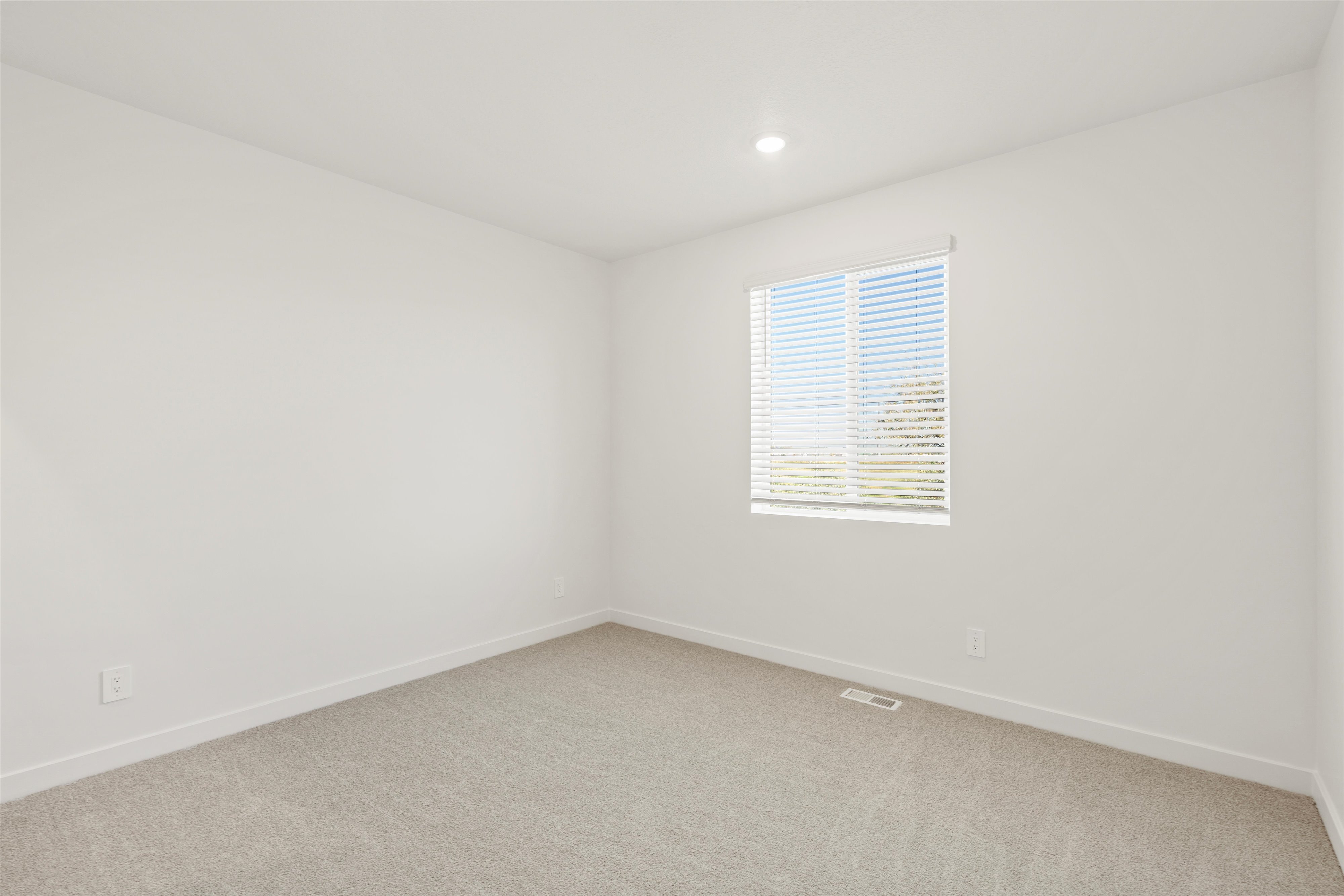 **DISCLAIMER** Interior package may vary. Bright interior room featuring a window with horizontal blinds, neutral carpeting, white baseboards, and a recessed ceiling light