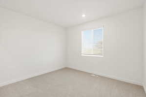 **DISCLAIMER** Interior package may vary. Bright interior room featuring a window with horizontal blinds, neutral carpeting, white baseboards, and a recessed ceiling light
