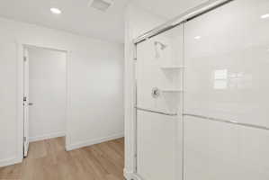 **DISCLAIMER** Interior package may vary. Shower enclosure featuring subway tile surround, glass sliding doors, built-in shelving, a rainfall showerhead, and a bright chrome faucet