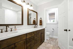 Dual wood-finish vanities with undermount sinks, bronze fixtures, and stone countertops