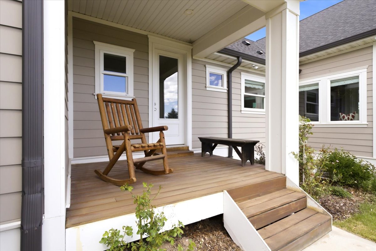 Covered porch featuring wood-finish decking, white trim, and siding