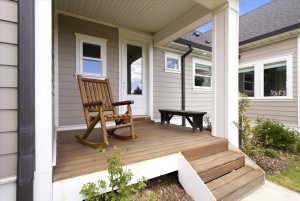 Covered porch featuring wood-finish decking, white trim, and siding