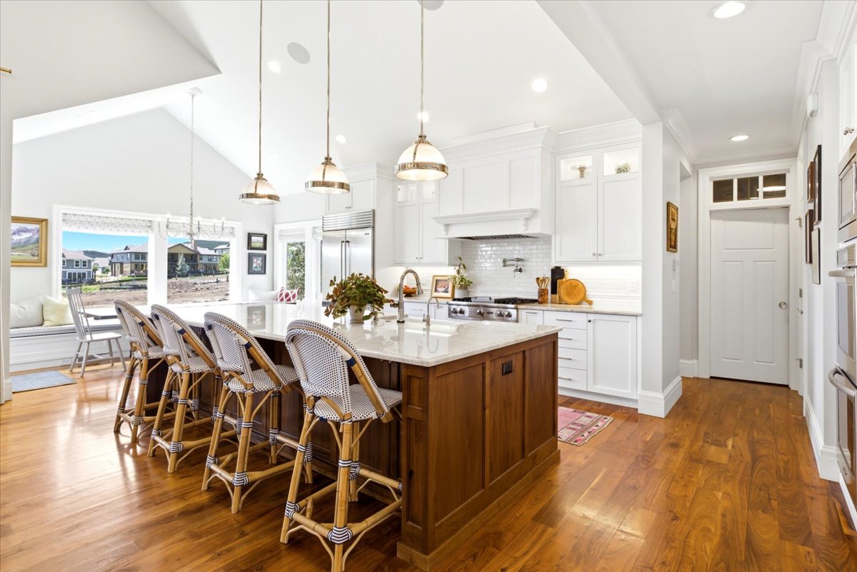 Gourmet kitchen featuring a large central island with seating, stainless steel appliances, and white cabinetry