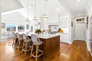Gourmet kitchen featuring a large central island with seating, stainless steel appliances, and white cabinetry