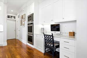 Integrated office nook featuring built-in cabinetry, under-cabinet lighting, a stone countertop, and wood-finish flooring
