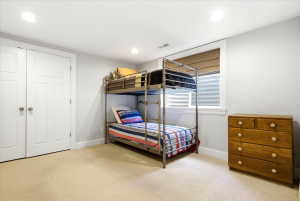 Carpeted room featuring recessed lighting, a window with a blind, and two white panel doors