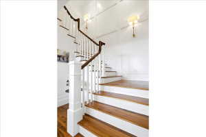 Hardwood staircase featuring white risers and balusters, and a dark wood-finish handrail