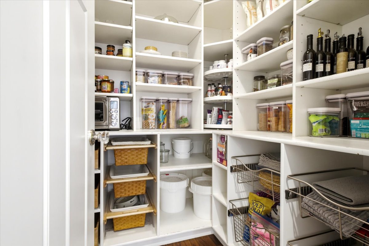 Built-in pantry system featuring white shelving, integrated wire baskets, pull-out storage, and a corner lazy Susan