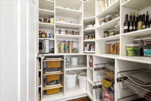 Built-in pantry system featuring white shelving, integrated wire baskets, pull-out storage, and a corner lazy Susan