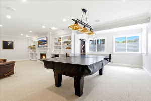 Carpeted recreation room featuring a central game table, recessed lighting, and a linear chandelier