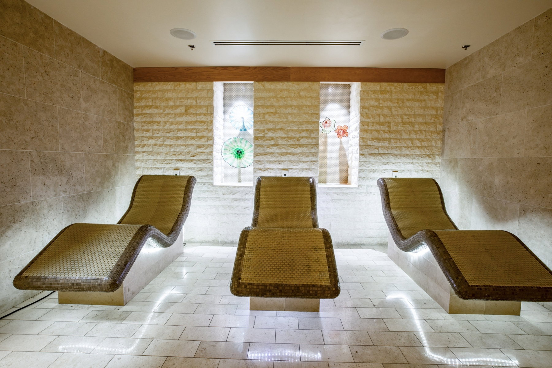 Spa-style relaxation area featuring three chaise lounges with integrated underlighting
