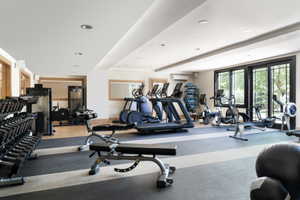 Dedicated fitness space featuring ample natural light, recessed ceiling lighting, a mirrored wall section, and a combination of wood-finish and rubber flooring
