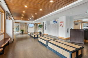 Spacious common area featuring wood-finish flooring, a wood-slat ceiling, recessed lighting, and stone accent walls