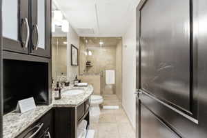 Bathroom featuring a granite countertop vanity with an undermount sink, dark wood cabinetry, and an enclosed shower with glass walls and tiled surround