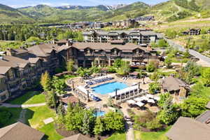 Central resort-style pool area with surrounding lounge seating, mature landscaping, and mountain backdrop