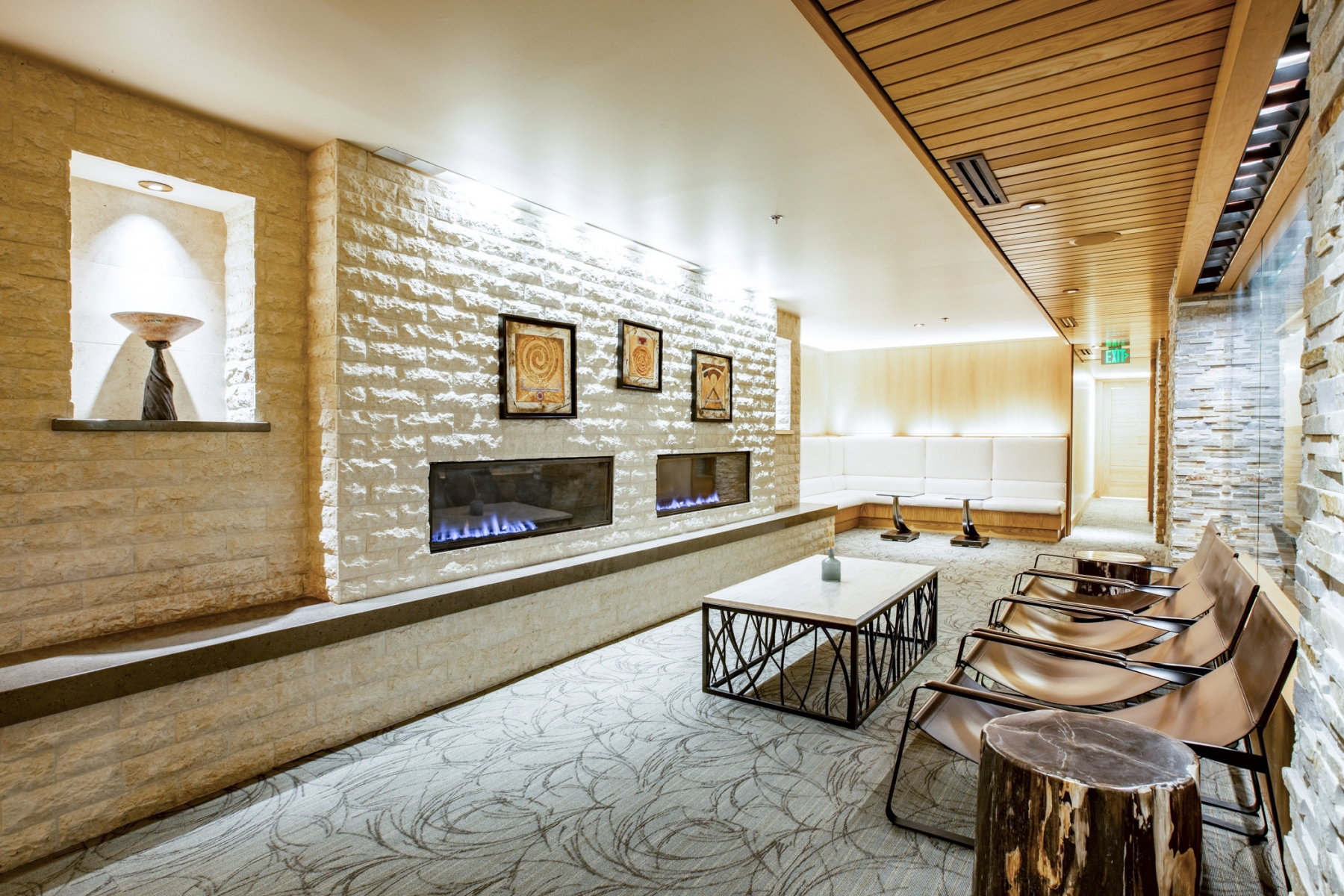 Stone-clad accent wall featuring two linear fireplaces and a built-in display nook