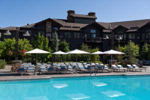 Expansive outdoor swimming pool with surrounding lounge chairs and white umbrellas